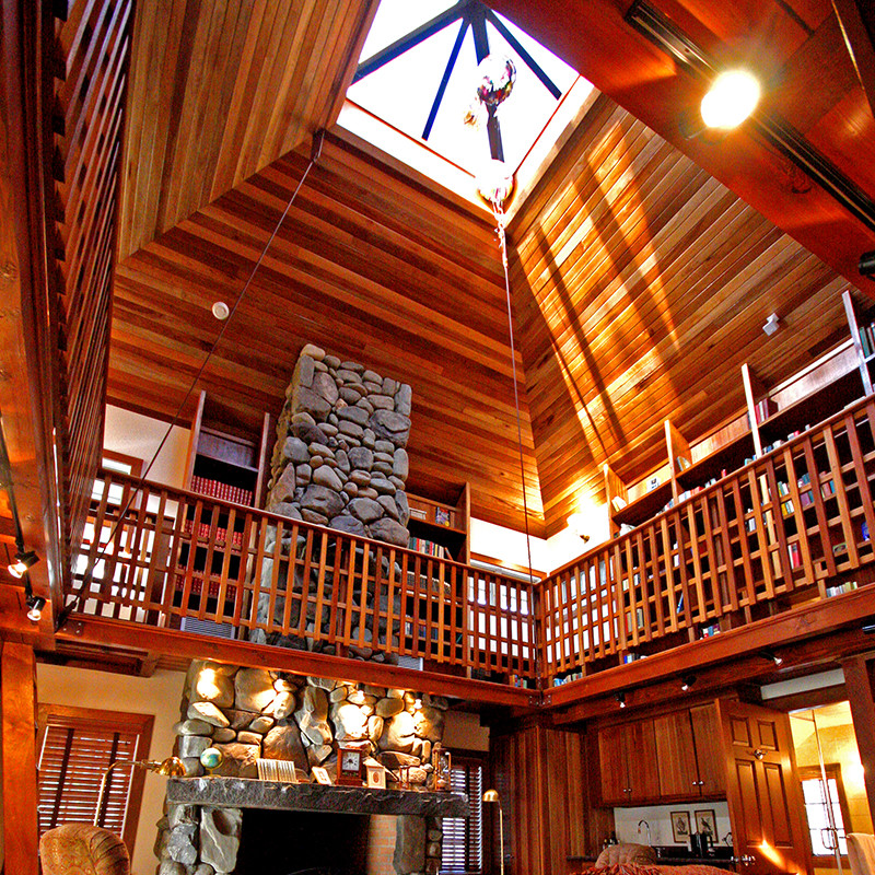 Idée de décoration pour une grande salle de séjour craftsman ouverte avec un mur beige, un sol en bois brun, une cheminée standard et un manteau de cheminée en pierre.