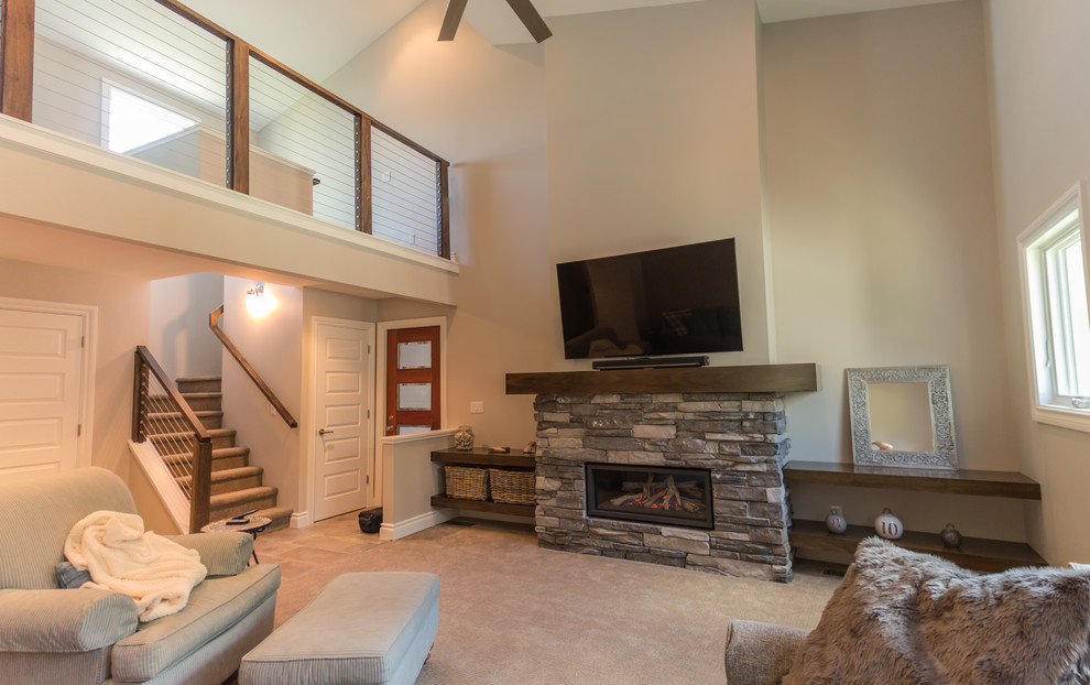 Foto de sala de estar tipo loft de estilo americano de tamaño medio con paredes beige, moqueta, marco de chimenea de piedra, televisor colgado en la pared y suelo beige