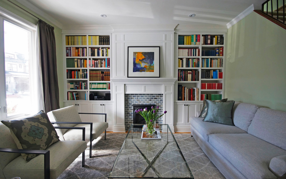Immagine di un soggiorno minimal di medie dimensioni e chiuso con libreria, pareti verdi, parquet chiaro, camino classico, cornice del camino in mattoni e nessuna TV