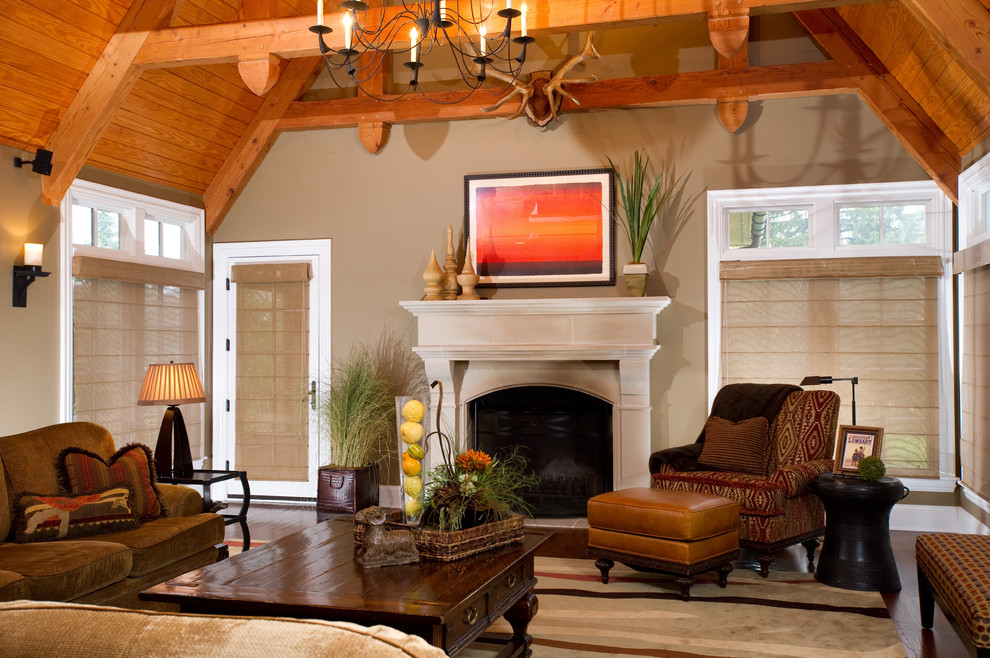 Cette photo montre une grande salle de séjour éclectique avec un mur beige, parquet foncé, une cheminée standard, aucun téléviseur, un manteau de cheminée en bois et un sol marron.