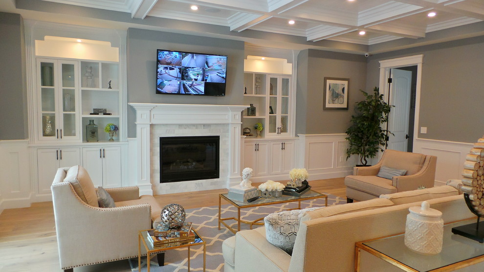 Diseño de sala de estar abierta de estilo americano grande con paredes grises, suelo de madera clara, todas las chimeneas, marco de chimenea de baldosas y/o azulejos y televisor colgado en la pared