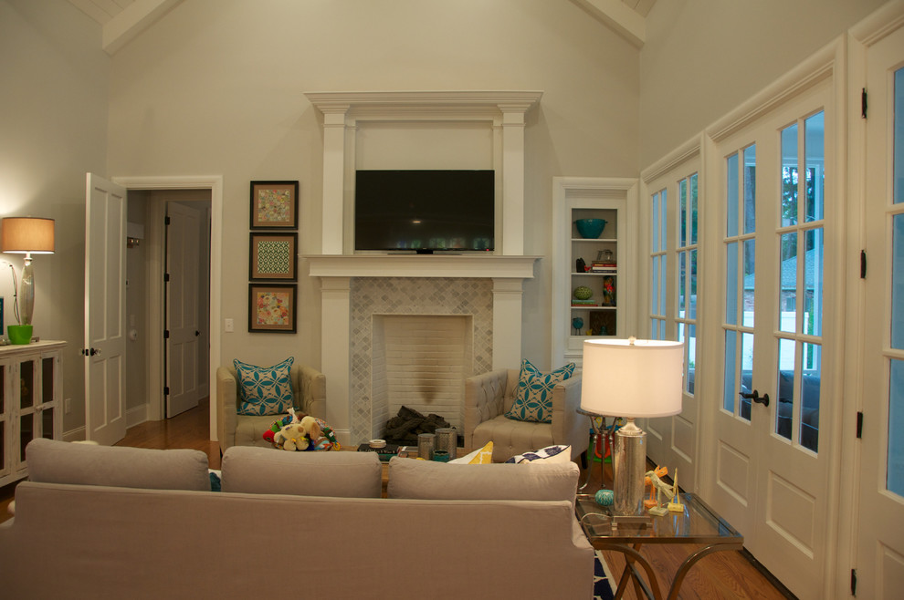 Example of a large classic open concept medium tone wood floor family room design in Jackson with gray walls, a standard fireplace, a stone fireplace and a wall-mounted tv