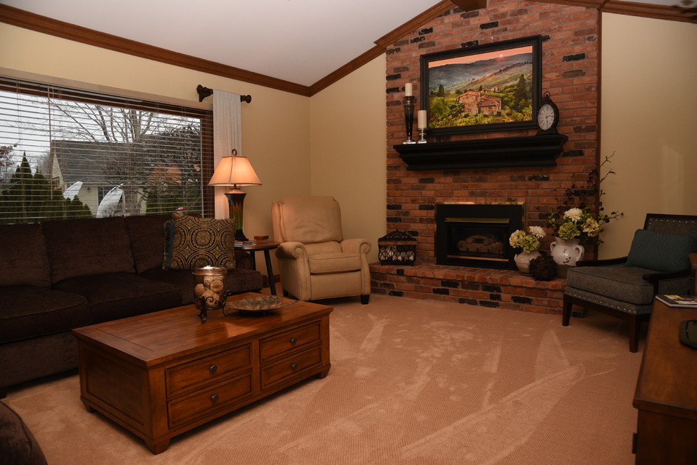 Immagine di un grande soggiorno chic aperto con pareti beige, camino classico, cornice del camino in mattoni e TV autoportante