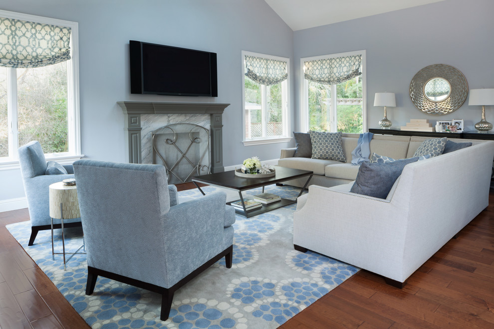 На фото: большая открытая гостиная комната в стиле неоклассика (современная классика) с синими стенами, паркетным полом среднего тона, стандартным камином, фасадом камина из камня и телевизором на стене с