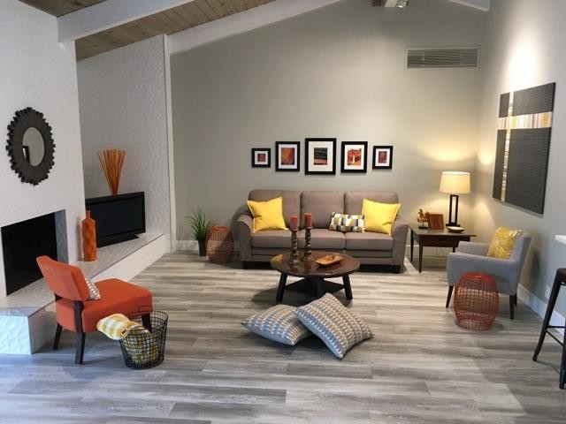 Cette image montre une salle de séjour design de taille moyenne et ouverte avec un mur gris, sol en stratifié, une cheminée standard, un manteau de cheminée en carrelage, un téléviseur indépendant et un sol gris.