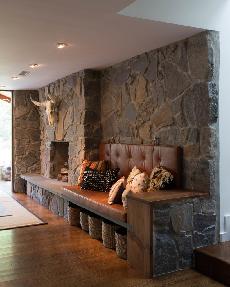 Exemple d'une très grande salle de séjour rétro ouverte avec un mur gris, un sol en bois brun, une cheminée double-face, un manteau de cheminée en pierre et un sol marron.