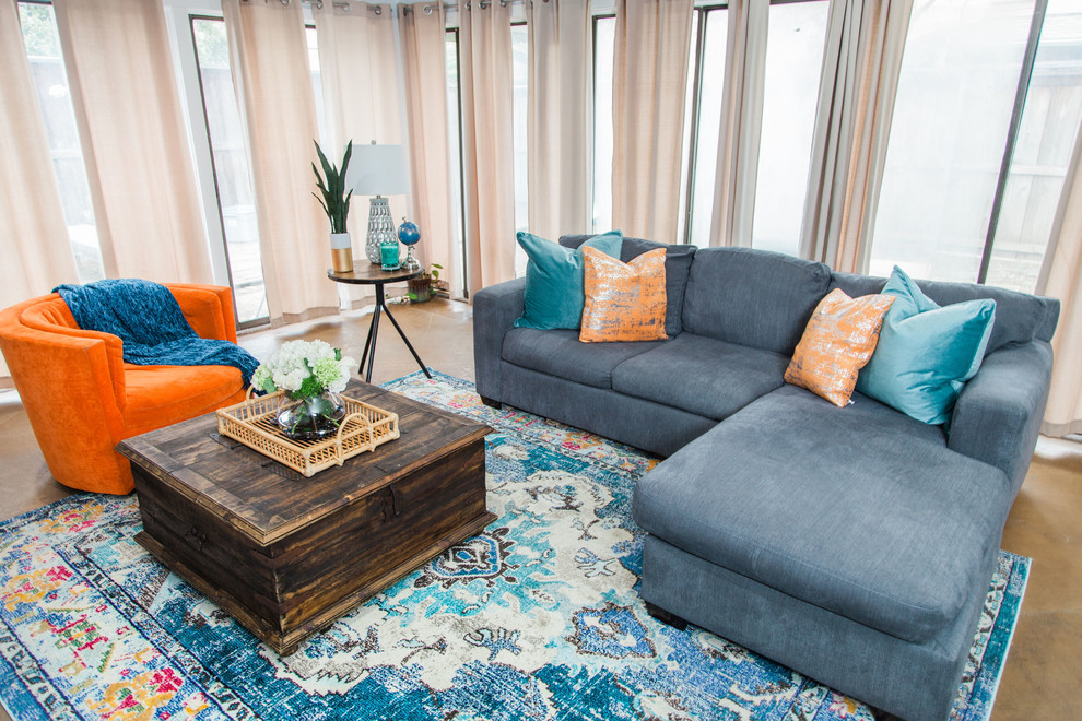 Modelo de sala de estar abierta clásica renovada de tamaño medio sin chimenea con paredes azules, suelo de cemento, televisor colgado en la pared y suelo marrón