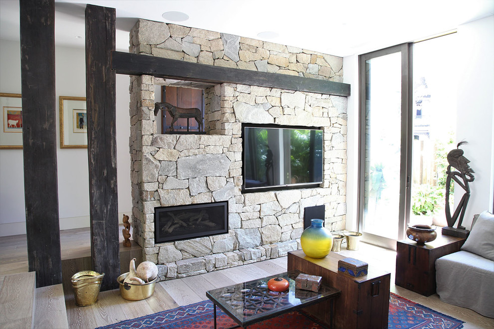 Ejemplo de sala de estar bohemia con suelo de madera en tonos medios, todas las chimeneas, marco de chimenea de piedra, suelo multicolor y pared multimedia