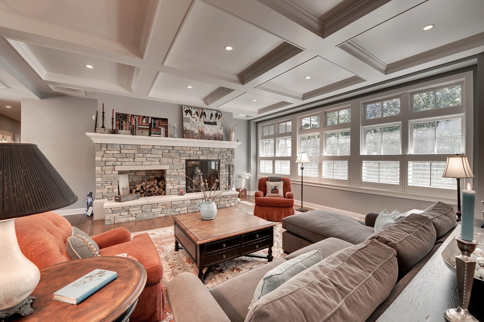 Пример оригинального дизайна: открытая гостиная комната в классическом стиле с серыми стенами, паркетным полом среднего тона, стандартным камином и фасадом камина из камня без телевизора