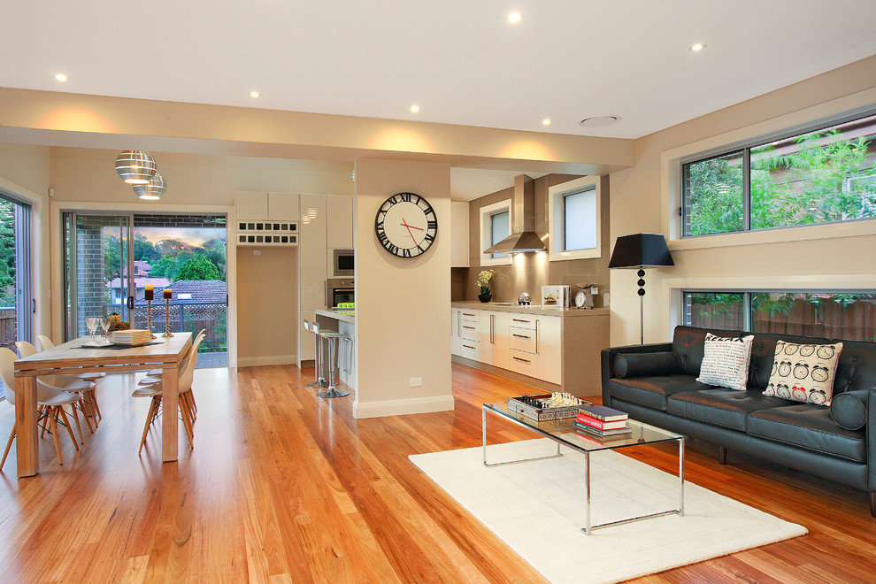 Cette image montre une salle de séjour design ouverte avec un mur beige et un sol en bois brun.
