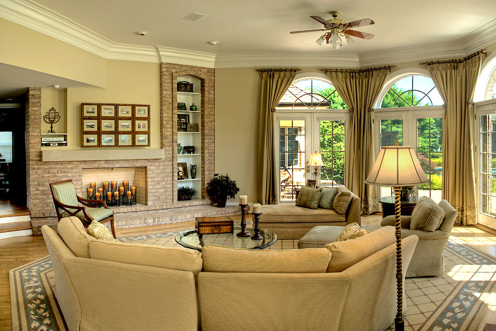 Foto de sala de estar abierta tradicional grande con paredes beige, suelo de madera en tonos medios, todas las chimeneas, marco de chimenea de ladrillo y suelo beige