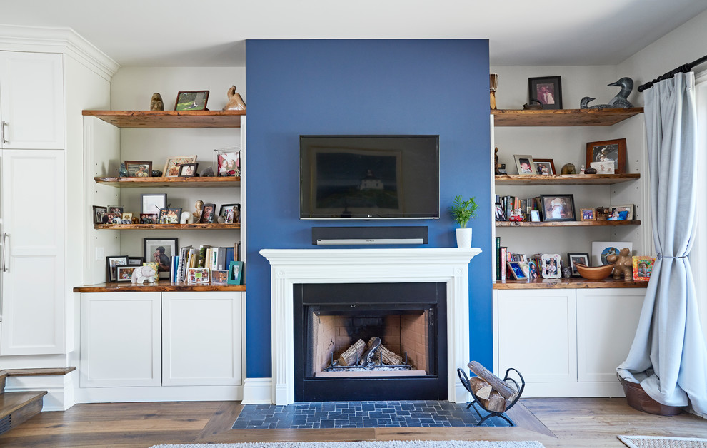 Imagen de sala de estar tipo loft tradicional renovada grande con paredes azules, suelo de madera en tonos medios, todas las chimeneas, marco de chimenea de madera, pared multimedia y suelo marrón