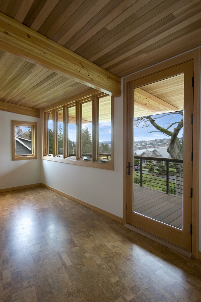 Cette image montre une grande salle de séjour minimaliste fermée avec un mur blanc, un sol en bois brun et aucune cheminée.