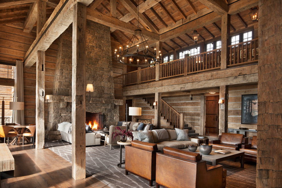 Expansive rustic open plan games room in Other with brown walls, medium hardwood flooring, a standard fireplace, a stone fireplace surround and brown floors.
