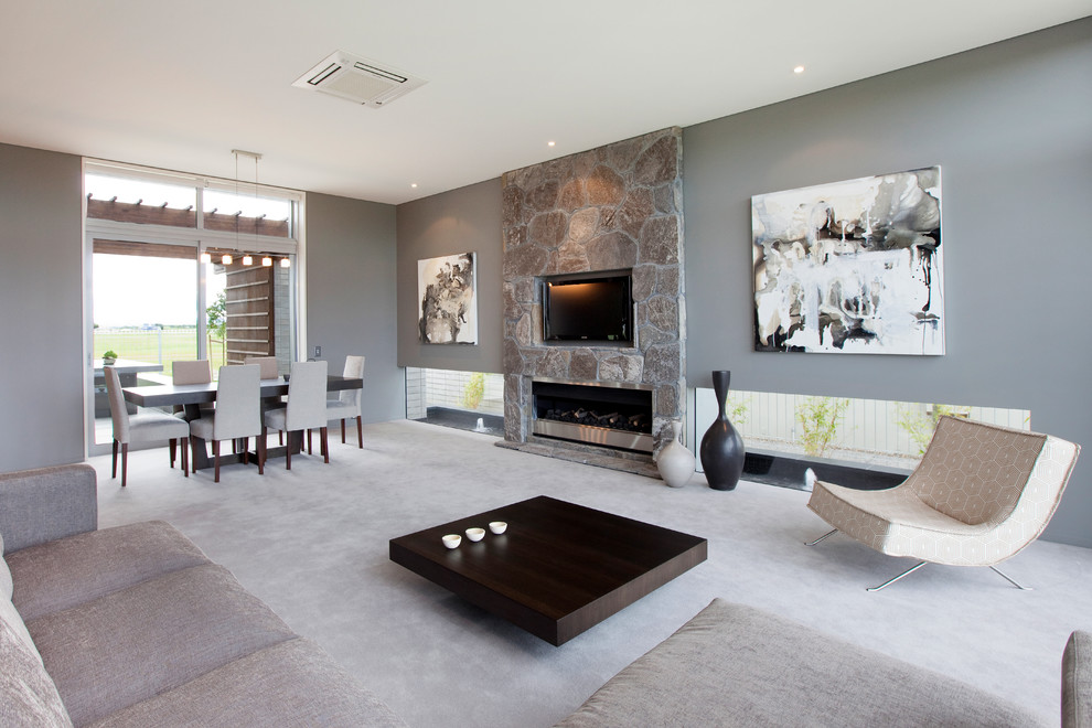 Großes, Offenes Modernes Wohnzimmer mit grauer Wandfarbe, Teppichboden, Gaskamin, Multimediawand und Kaminumrandung aus Stein in Hamilton