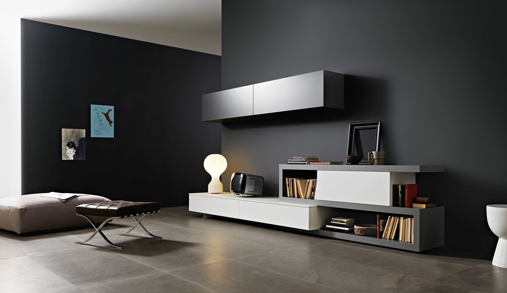 Immagine di un soggiorno moderno con libreria, pareti grigie, pavimento in cemento e TV autoportante