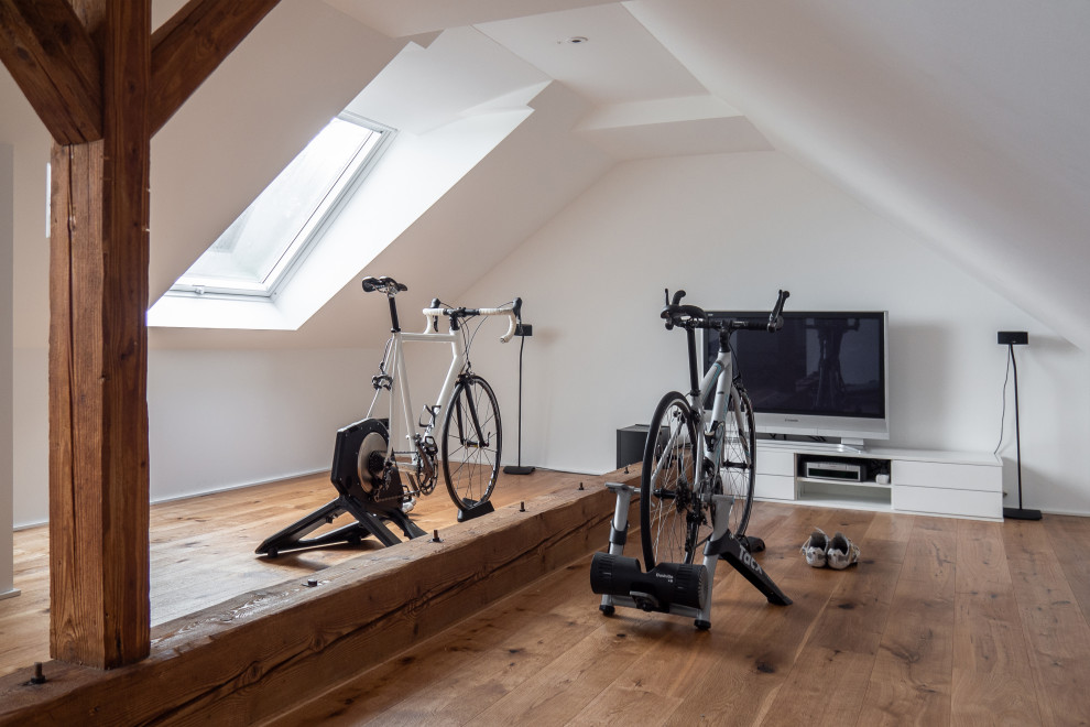 Multifunktionaler, Mittelgroßer Moderner Fitnessraum mit weißer Wandfarbe, braunem Holzboden, braunem Boden und gewölbter Decke in Dortmund