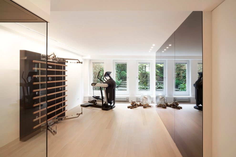Multifunktionaler Moderner Fitnessraum mit weißer Wandfarbe und hellem Holzboden in Köln