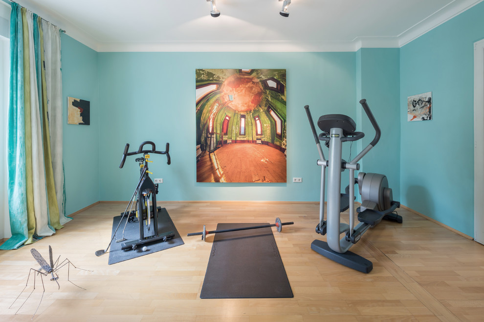 Multifunktionaler, Mittelgroßer Stilmix Fitnessraum mit hellem Holzboden und blauer Wandfarbe in Köln