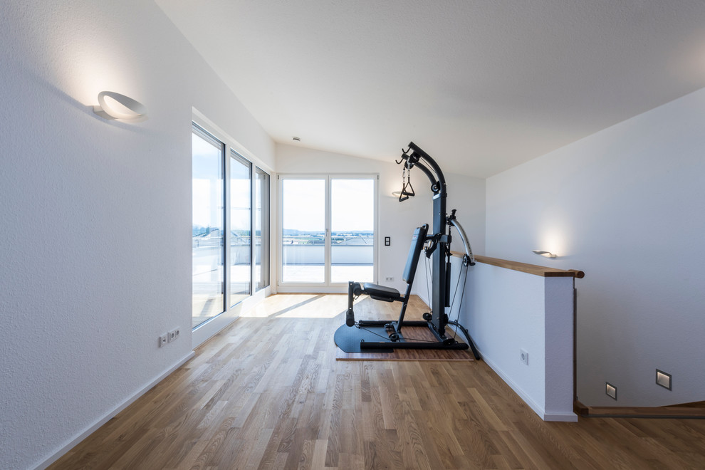 Multifunktionaler, Mittelgroßer Moderner Fitnessraum mit weißer Wandfarbe und braunem Holzboden in Sonstige