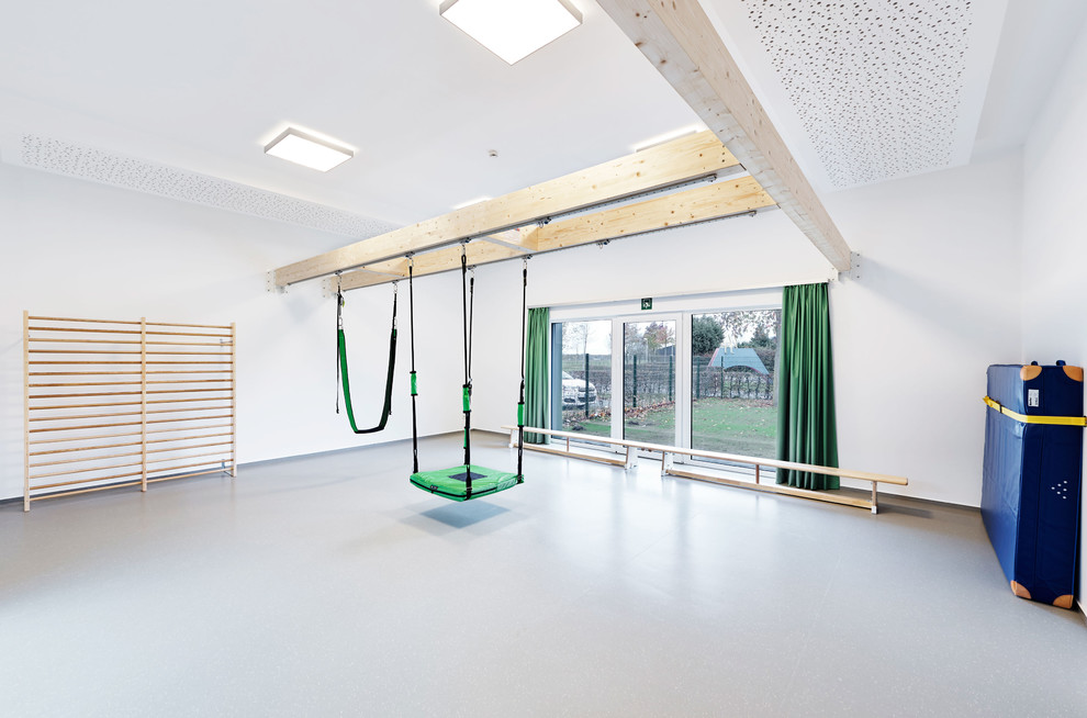 Großer Moderner Fitnessraum mit weißer Wandfarbe und grauem Boden in Düsseldorf