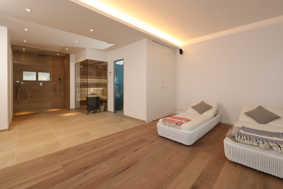Großer Moderner Fitnessraum mit weißer Wandfarbe und braunem Holzboden in Sonstige