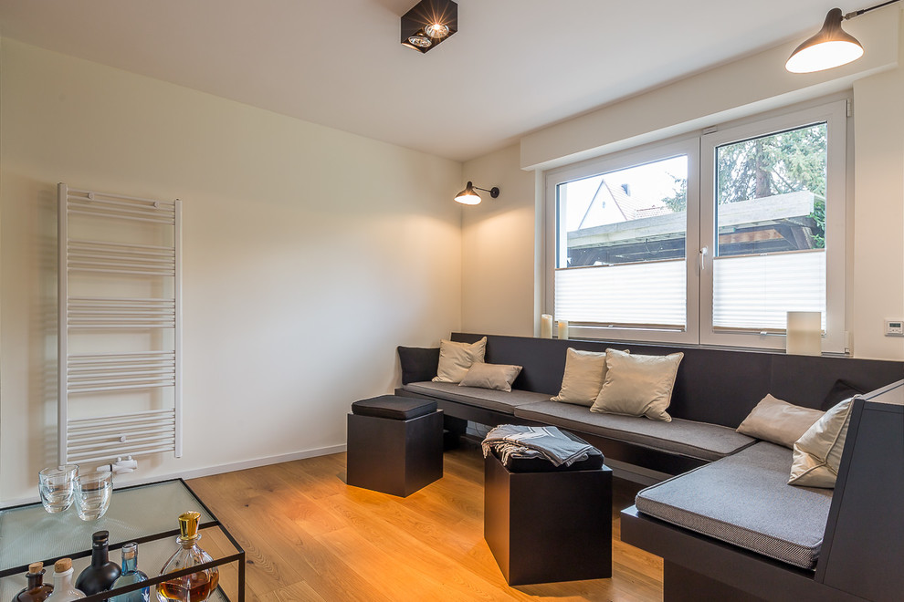 Mittelgroßer Moderner Fitnessraum mit weißer Wandfarbe, braunem Holzboden und braunem Boden in Dortmund