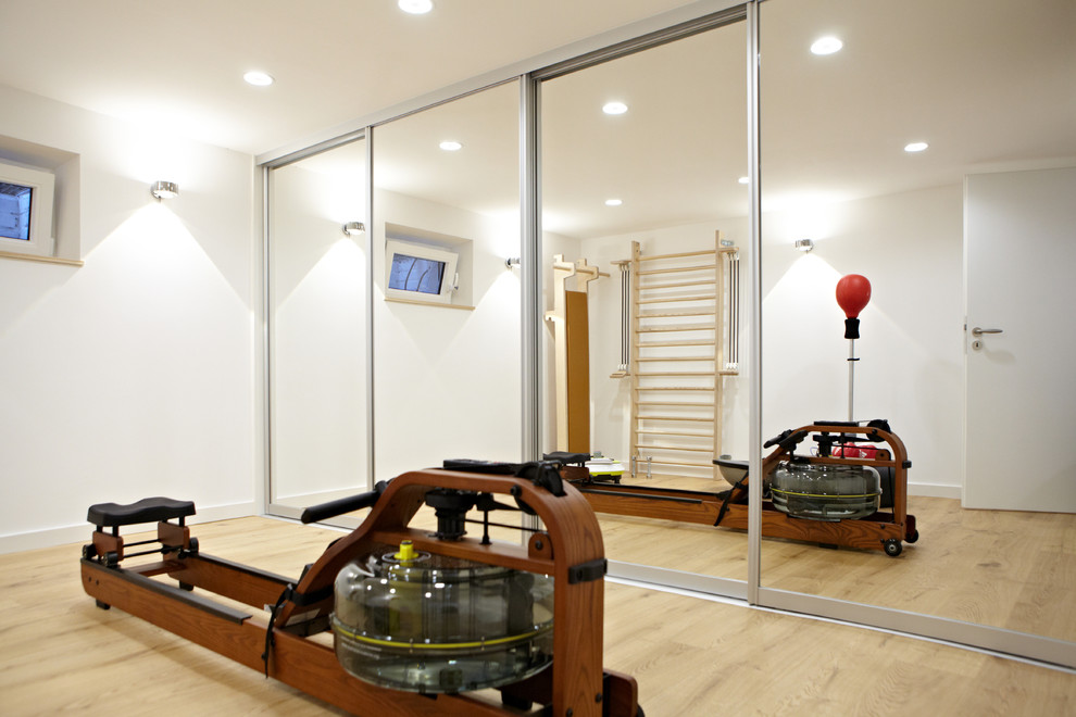 Inspiration for a medium sized modern home weight room in Dusseldorf with white walls and light hardwood flooring.