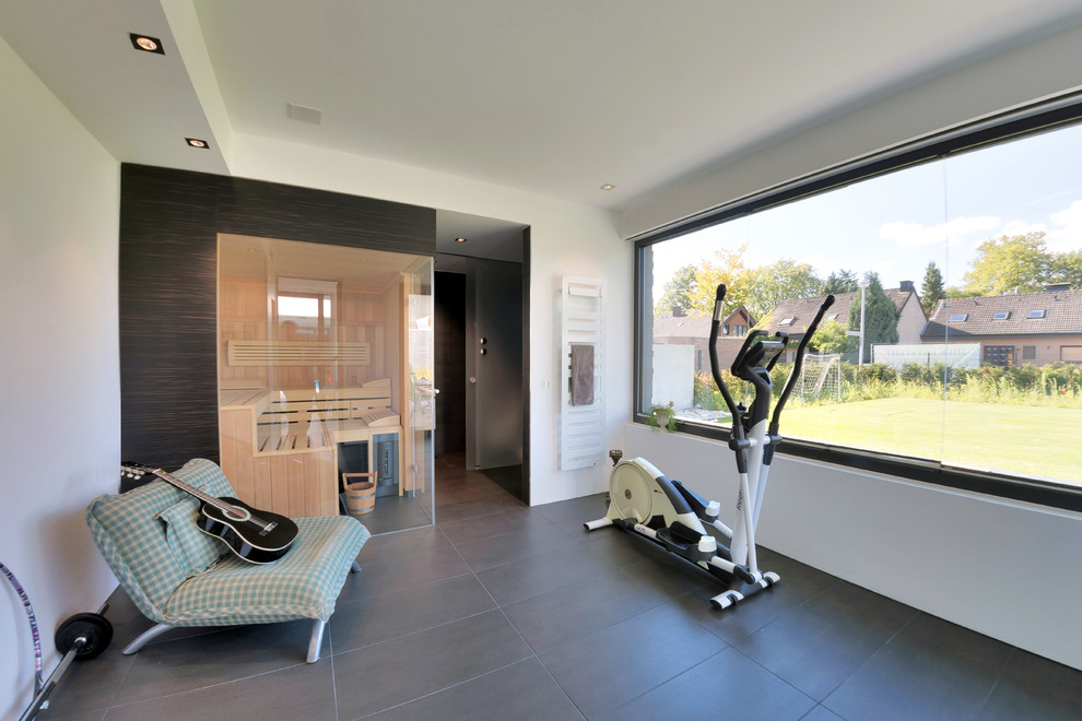 Multifunktionaler Moderner Fitnessraum mit weißer Wandfarbe, Betonboden und grauem Boden in Dortmund