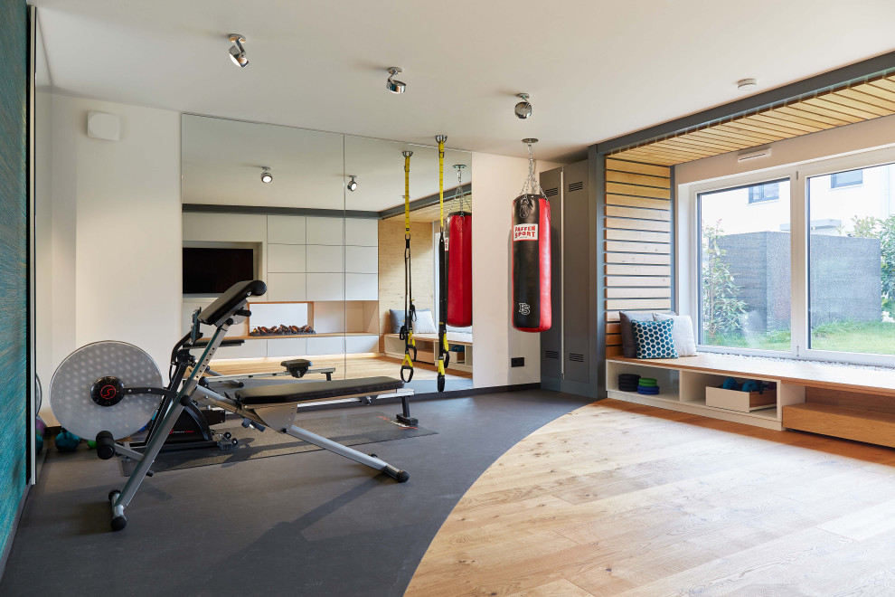 Multifunktionaler, Großer Moderner Fitnessraum mit weißer Wandfarbe, braunem Holzboden und braunem Boden in Frankfurt am Main