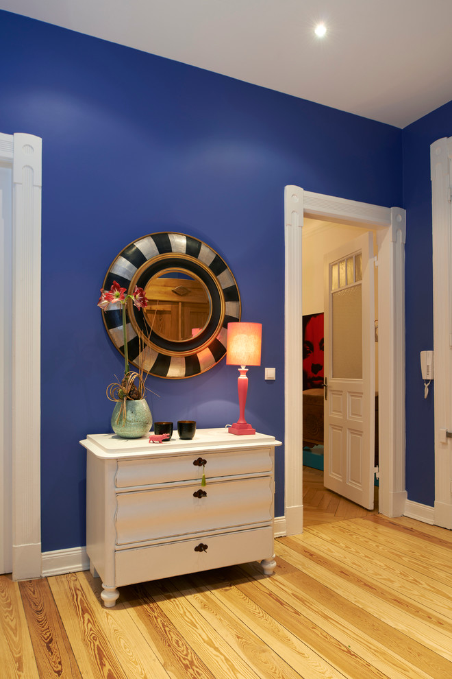 Ispirazione per un ingresso o corridoio minimal di medie dimensioni con pareti blu e parquet chiaro