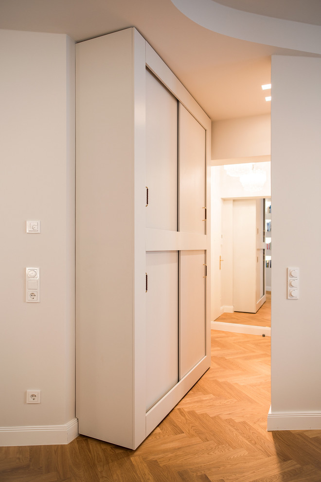 Idée de décoration pour un petit couloir design avec un mur gris, parquet clair et un sol marron.