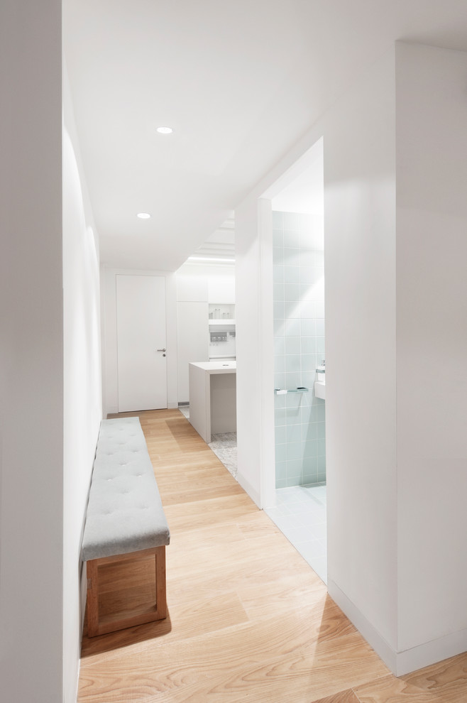 Cette image montre un couloir minimaliste de taille moyenne avec un mur blanc, parquet clair et un sol beige.