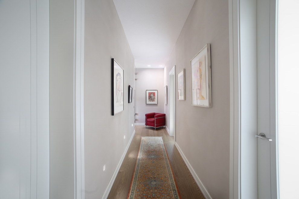 Ispirazione per un piccolo ingresso o corridoio moderno con pareti bianche, pavimento in legno massello medio e pavimento marrone