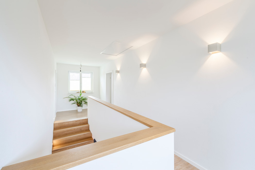 Foto di un ingresso o corridoio minimalista di medie dimensioni con pareti bianche, parquet chiaro e pavimento marrone