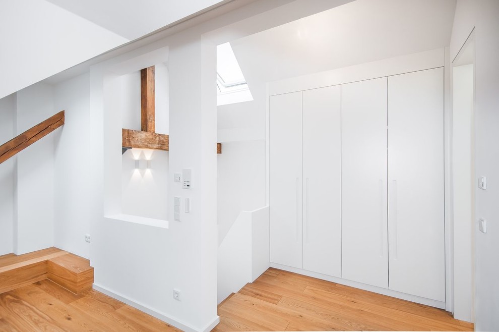 Ispirazione per un ingresso o corridoio design di medie dimensioni con pareti bianche e pavimento in legno massello medio