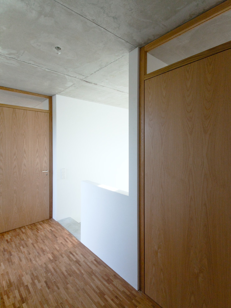 На фото: коридор среднего размера в стиле модернизм с белыми стенами, паркетным полом среднего тона и коричневым полом