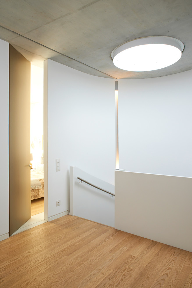 Ejemplo de recibidores y pasillos contemporáneos de tamaño medio con paredes blancas y suelo de madera clara