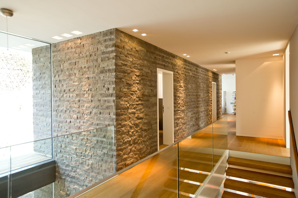 Aménagement d'un grand couloir contemporain avec un mur blanc et un sol en bois brun.