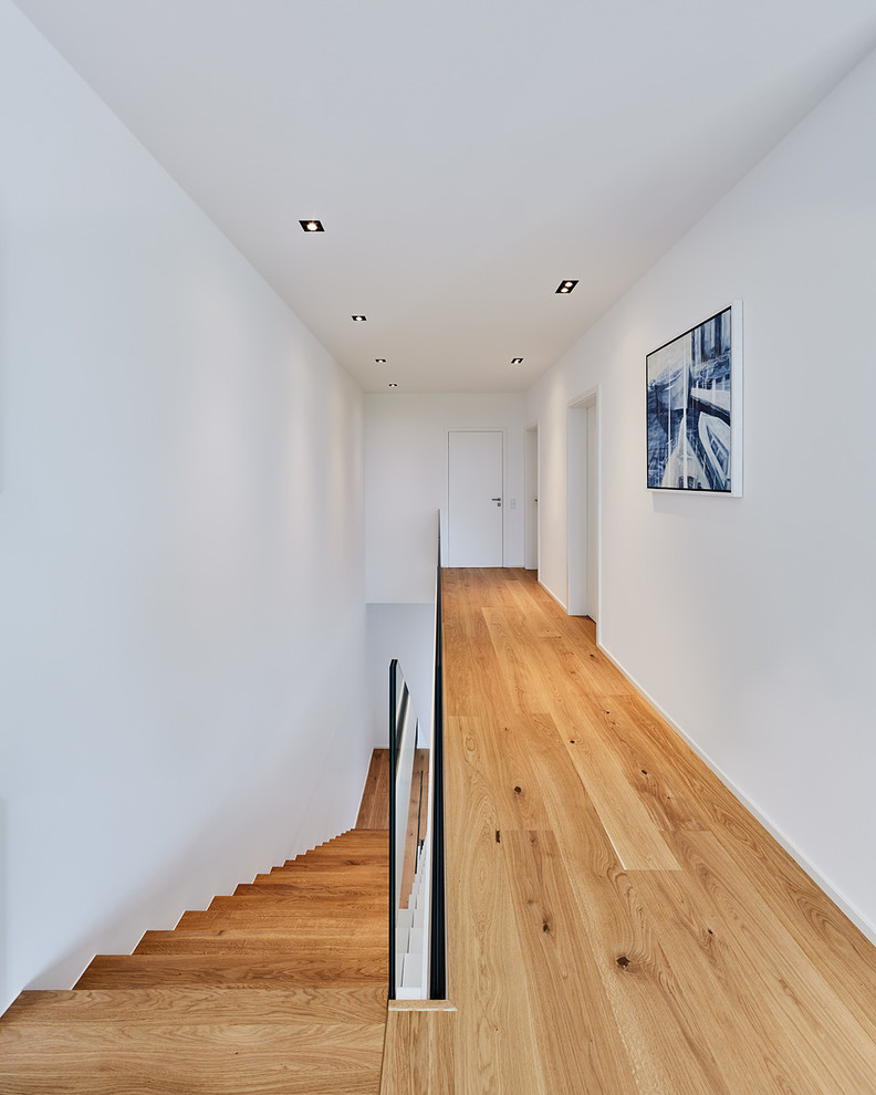 Immagine di un grande ingresso o corridoio nordico con pareti bianche, pavimento in legno massello medio e pavimento marrone