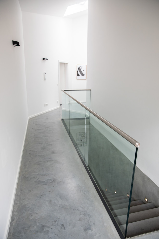 Aménagement d'un couloir moderne de taille moyenne avec un mur blanc, sol en béton ciré et un sol gris.