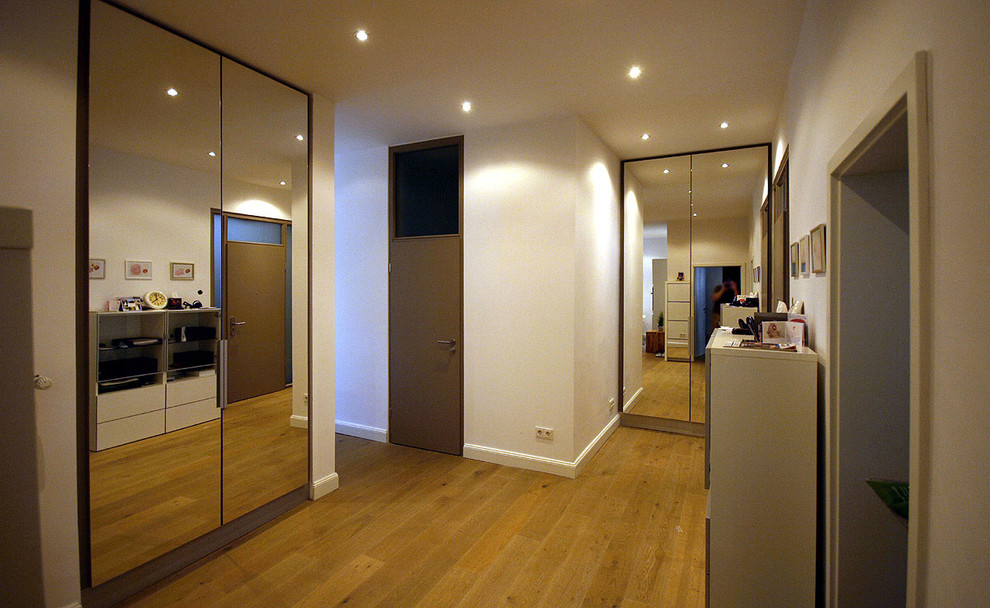 Стильный дизайн: коридор среднего размера в современном стиле с белыми стенами, паркетным полом среднего тона и коричневым полом - последний тренд
