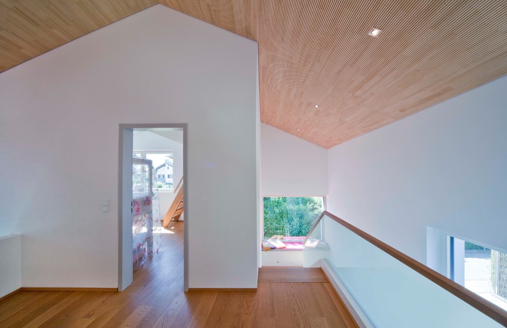 Esempio di un grande ingresso o corridoio minimal con pareti bianche, pavimento in legno massello medio e pavimento marrone