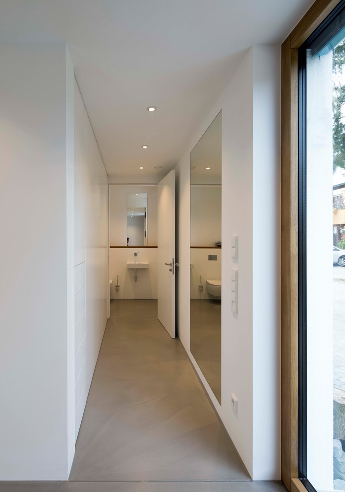 Idées déco pour un petit couloir moderne avec un mur blanc, sol en béton ciré et un sol gris.