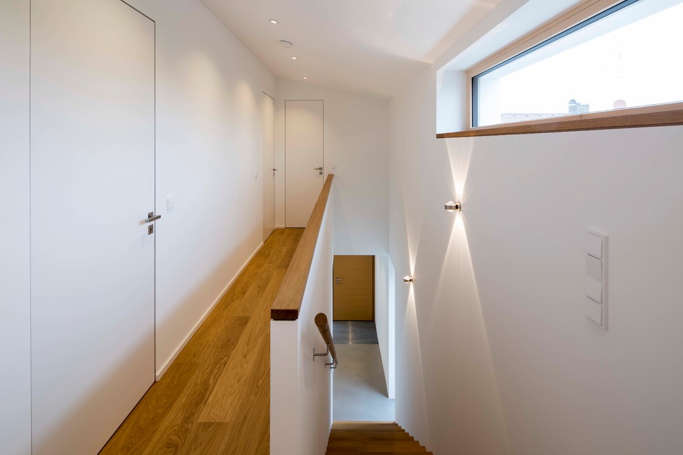 Idées déco pour un petit couloir contemporain avec un mur blanc, un sol en bois brun et un sol marron.