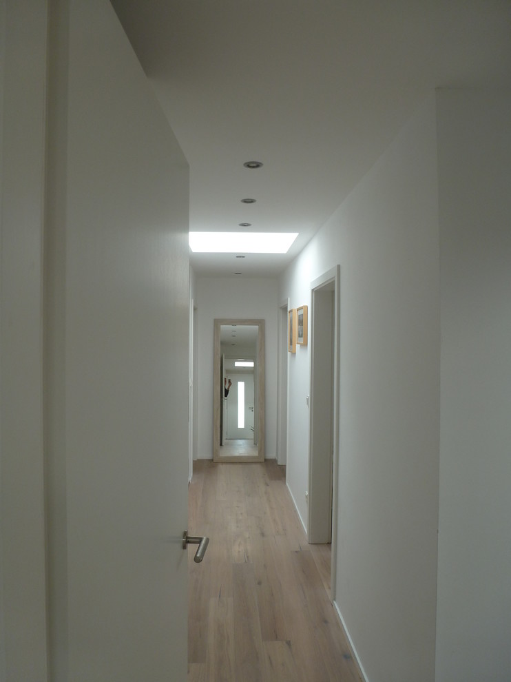 Exemple d'un petit couloir tendance avec un mur blanc et parquet peint.