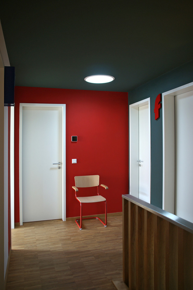 Moderner Flur mit roter Wandfarbe, hellem Holzboden und Tapetenwänden in Leipzig