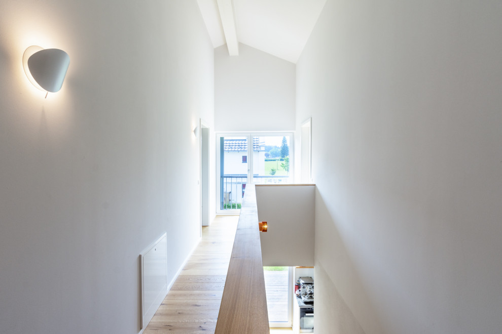 Esempio di un grande ingresso o corridoio contemporaneo con pareti bianche, pavimento in legno massello medio e pavimento marrone