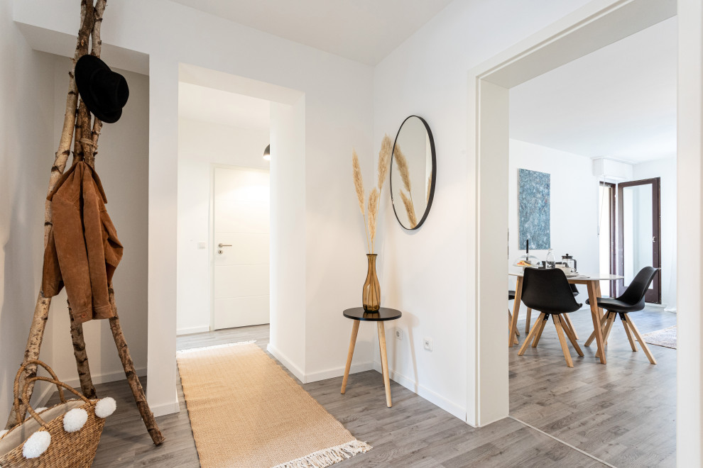 Example of a small danish laminate floor, gray floor and tray ceiling hallway design in Essen with white walls