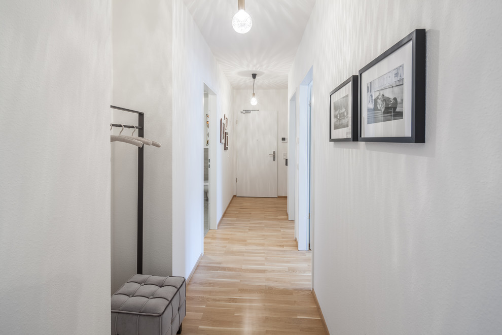 Foto på en liten funkis hall, med vita väggar, laminatgolv och brunt golv